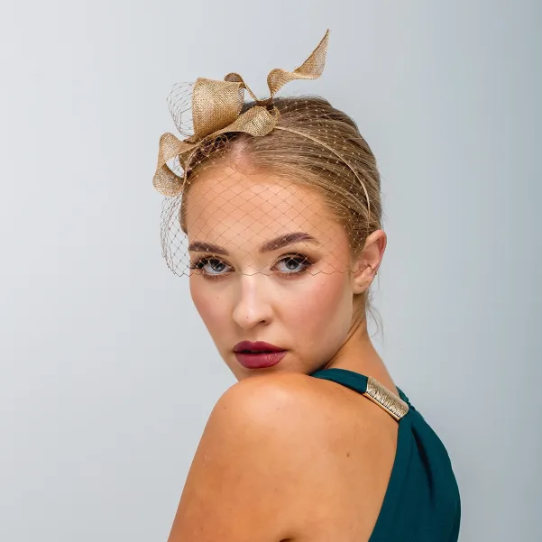 Złoty fascynator falująca kokarda z woalką.