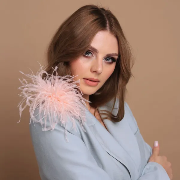 Brzoskwiniowa modna broszka z piórkami.