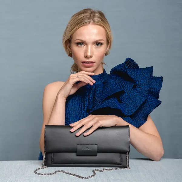 Czarna kopertówka skórzana do ręki i na łańcuszku.