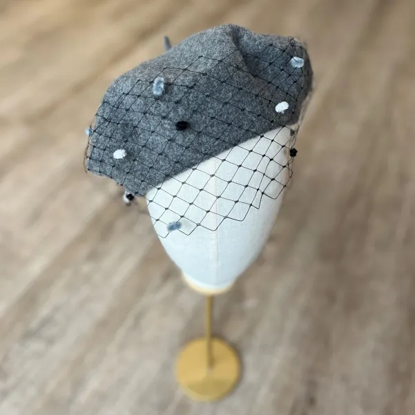 Szary beret z woalką w kropki.