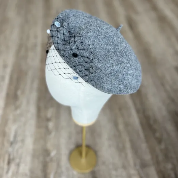 Szary beret z woalką w kropki.