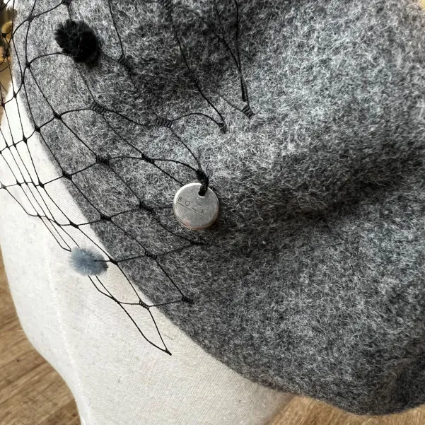 Szary beret z woalką w kropki.