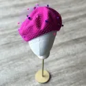 Różowy beret z nakrapianą woalką.