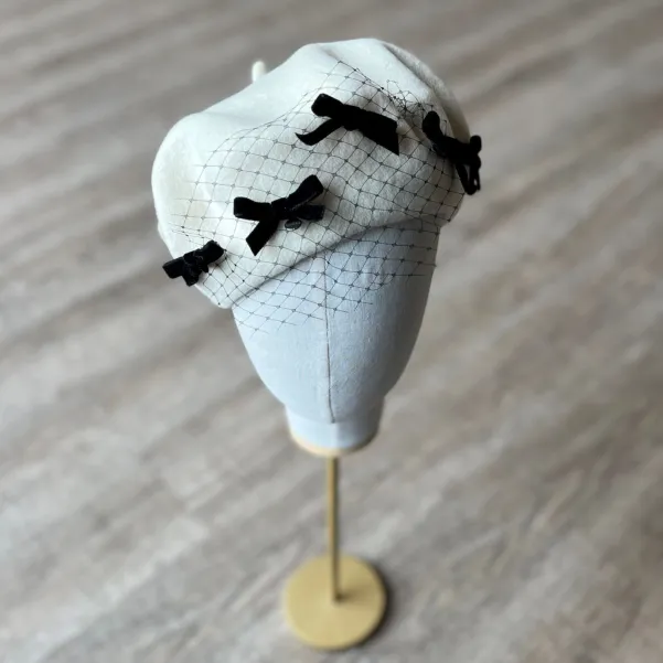 Kremowy beret z woalką i kokardkami.