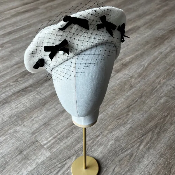 Kremowy beret z woalką i kokardkami.