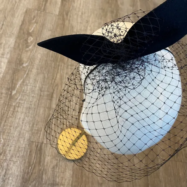 Gigantyczna czarna kokarda z woalką na głowę.