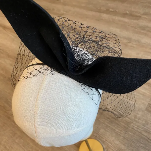 Gigantyczna czarna kokarda z woalką na głowę.