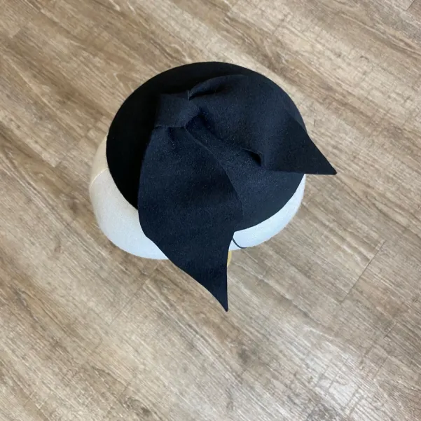 Czarne eleganckie nakrycie głowy kokardą.