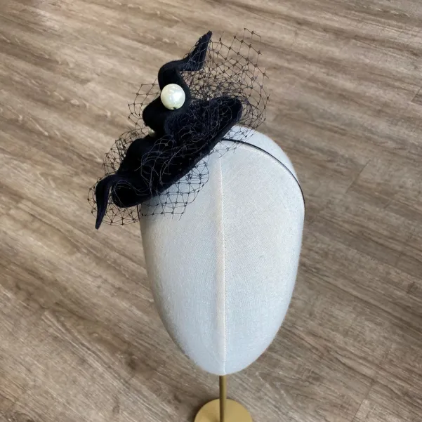 Czarny kapelusik z perłami i woalką.