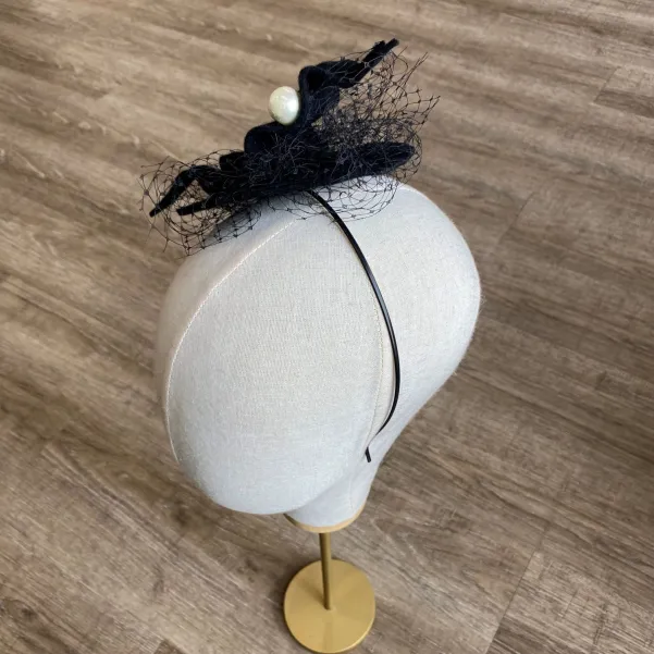 Czarny kapelusik z perłami i woalką.