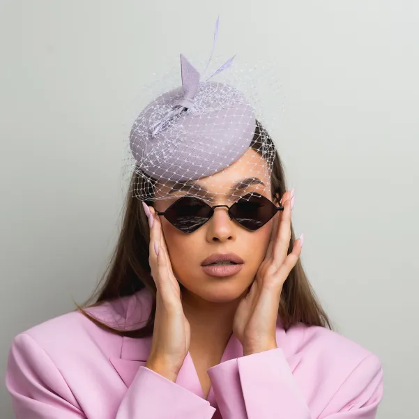 Liliowy kapelusik z piórkami i z woalką.