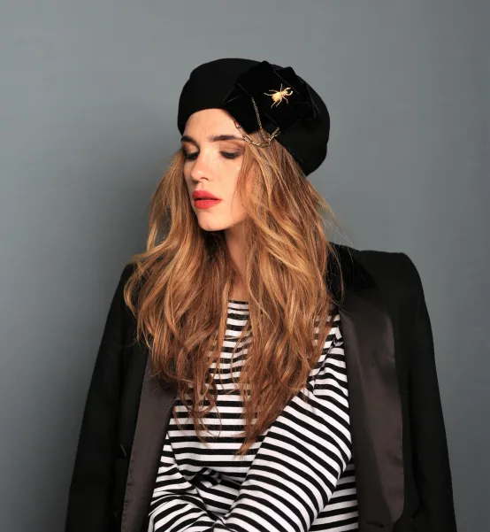 Stylowy beret z kokardą, łańcuchami i złotą ozdobą.