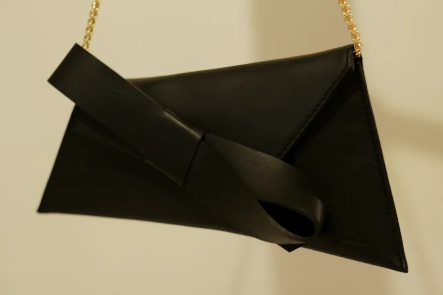 Czarna skórzana torebka z dużą kokardą.